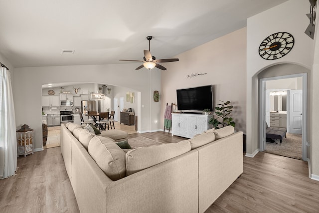 15003 Moonlight Mist Dr, Humble, TX 77346 - living room with arched walkways, light wood-type flooring, ceiling fan, lofted ceiling, and a chandelier