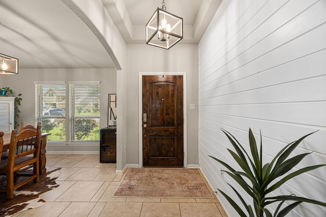 15003 Moonlight Mist Dr, Humble, TX 77346 - foyer featuring a chandelier, arched walkways, light tile patterned flooring, and wood walls