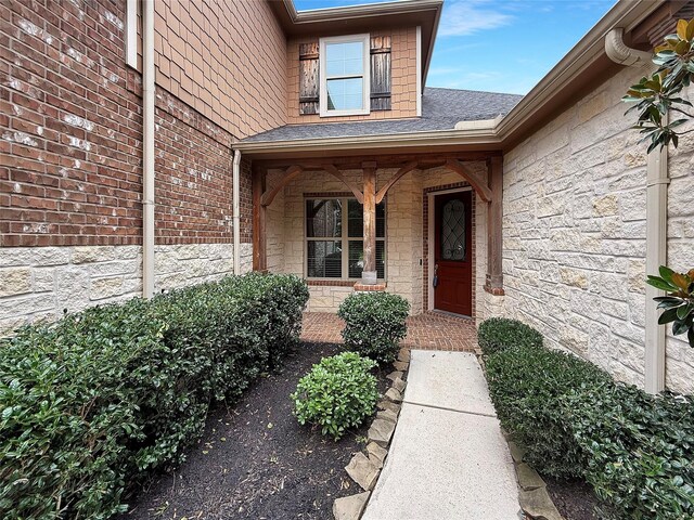 18614 Rimini Ridge Ct, Cypress, TX 77429 - view of exterior entry featuring stone siding, roof with shingles, and a porch