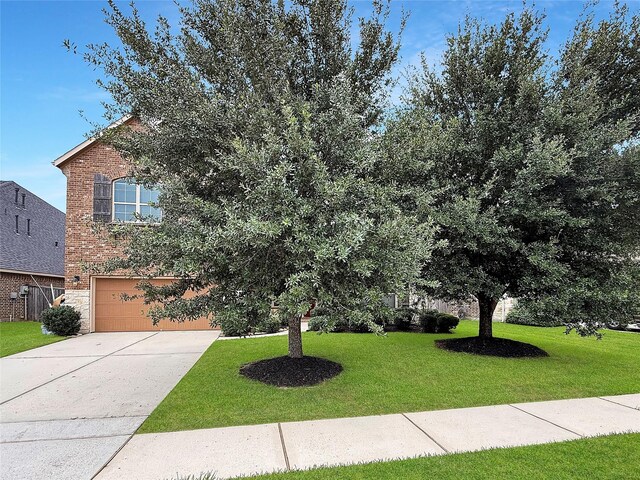 18614 Rimini Ridge Ct, Cypress, TX 77429 - view of property hidden behind natural elements featuring a front yard, an attached garage, concrete driveway, and brick siding