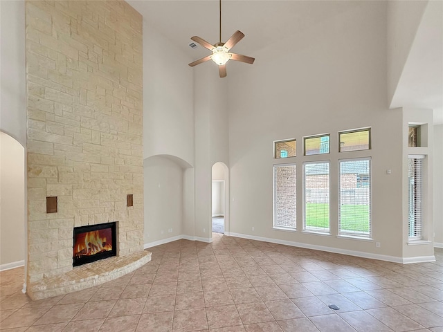 18614 Rimini Ridge Ct, Cypress, TX 77429 - unfurnished living room with a towering ceiling, ceiling fan, a fireplace, arched walkways, and light tile patterned flooring