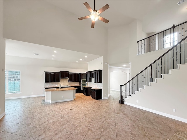 18614 Rimini Ridge Ct, Cypress, TX 77429 - kitchen with a high ceiling, an island with sink, a ceiling fan, open floor plan, and tasteful backsplash