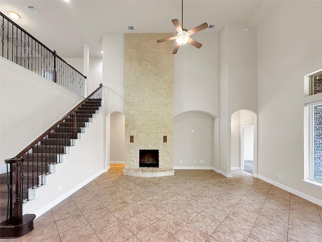 18614 Rimini Ridge Ct, Cypress, TX 77429 - unfurnished living room featuring a towering ceiling, a ceiling fan, arched walkways, stairs, and light tile patterned floors
