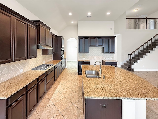 18614 Rimini Ridge Ct, Cypress, TX 77429 - kitchen with stainless steel appliances, arched walkways, light tile patterned flooring, decorative backsplash, and high vaulted ceiling