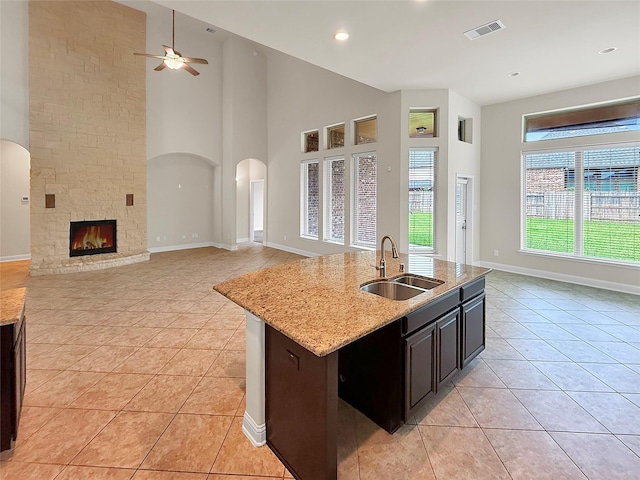 18614 Rimini Ridge Ct, Cypress, TX 77429 - kitchen featuring light tile patterned flooring, a ceiling fan, open floor plan, arched walkways, and light stone countertops