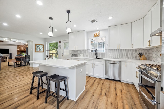 1818 Berryfield Dr, Houston, TX 77077 - kitchen with stainless steel appliances, light wood-style flooring, a breakfast bar, tasteful backsplash, and light countertops