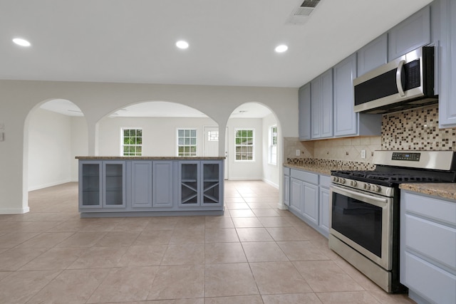 519 N Shady Ln, La Porte, TX 77571 - kitchen featuring appliances with stainless steel finishes, arched walkways, decorative backsplash, gray cabinets, and plenty of natural light