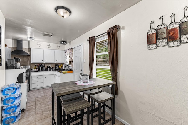 10434 Hinds St, Houston, TX 77034 - kitchen featuring wall chimney exhaust hood, white cabinetry, dark countertops, light tile patterned floors, and decorative backsplash
