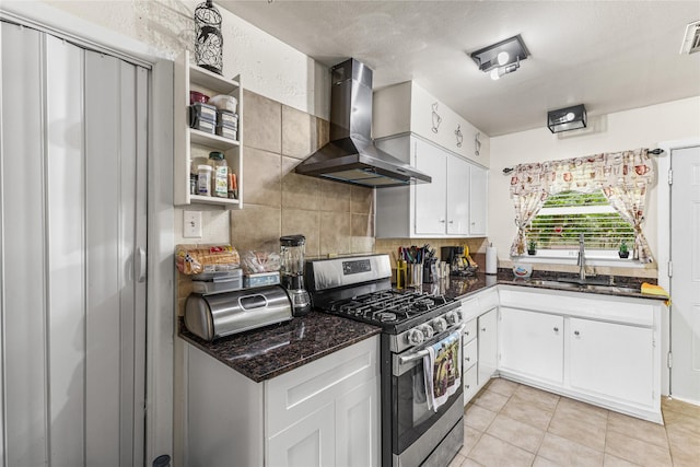 10434 Hinds St, Houston, TX 77034 - kitchen featuring stainless steel gas range, wall chimney range hood, white cabinets, light tile patterned flooring, and decorative backsplash