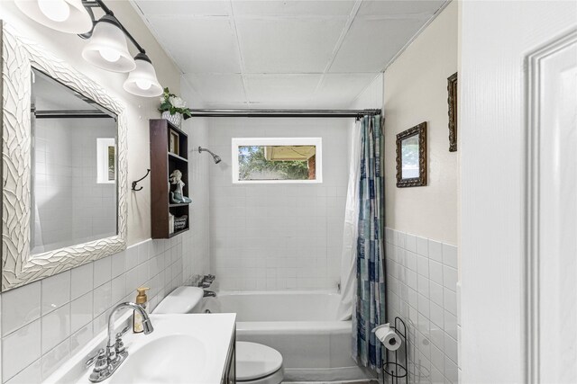 10434 Hinds St, Houston, TX 77034 - bathroom featuring tile walls, shower / tub combo with curtain, vanity, and a wainscoted wall