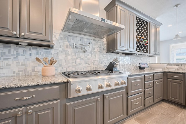 4107 Rainflower Ct, Fulshear, TX 77441 - kitchen with wall chimney range hood, stainless steel gas cooktop, gray cabinetry, and decorative backsplash