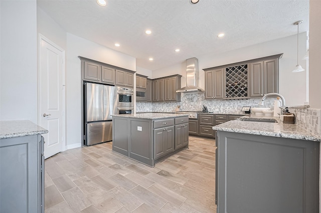 4107 Rainflower Ct, Fulshear, TX 77441 - kitchen featuring wall chimney exhaust hood, stainless steel appliances, gray cabinets, tasteful backsplash, and a kitchen island