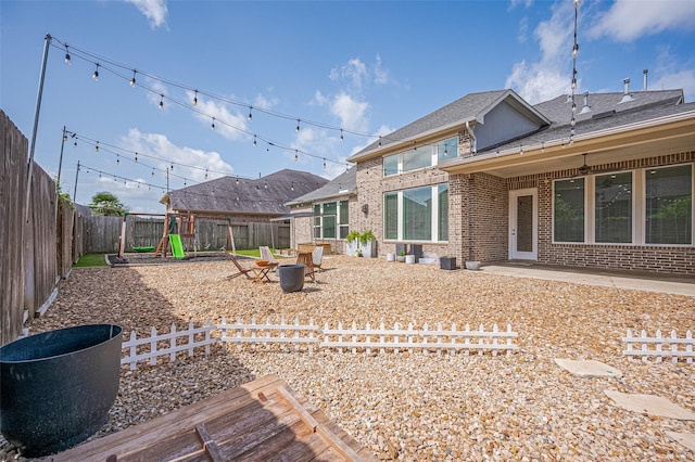 4107 Rainflower Ct, Fulshear, TX 77441 - back of property featuring brick siding, a playground, a fenced backyard, a patio area, and a shingled roof