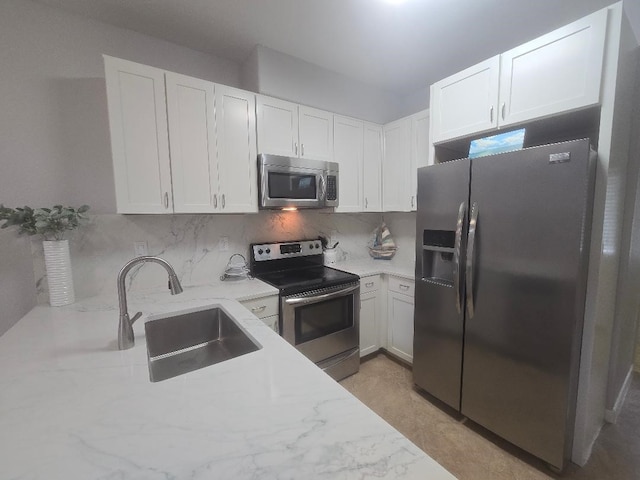 176 Capetown, Conroe, TX 77356 - kitchen with appliances with stainless steel finishes, light stone counters, white cabinets, and backsplash