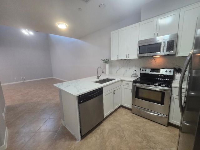 176 Capetown, Conroe, TX 77356 - kitchen with appliances with stainless steel finishes, tasteful backsplash, white cabinets, a peninsula, and light stone countertops