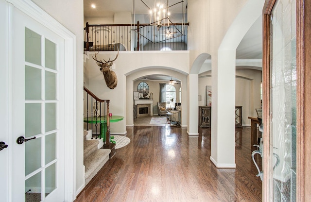 2512 Eagle Post Dr, Conroe, TX 77304 - foyer featuring arched walkways, a fireplace, wood finished floors, stairs, and a chandelier