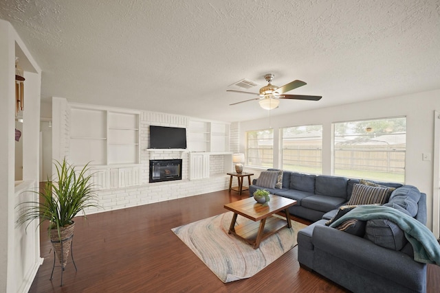 411 Pickford Dr, Katy, TX 77450 - living room with a textured ceiling, wood finished floors, a ceiling fan, healthy amount of natural light, and a brick fireplace