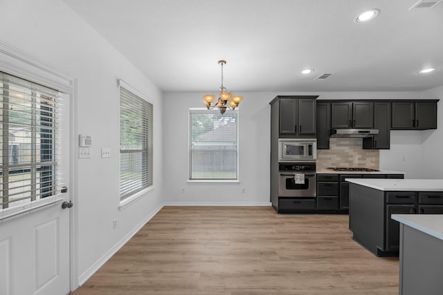 5918 Mahogany Way, Magnolia, TX 77354 - kitchen with appliances with stainless steel finishes, a chandelier, light countertops, decorative backsplash, and light wood-style floors