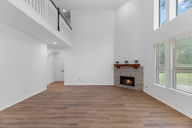 5918 Mahogany Way, Magnolia, TX 77354 - unfurnished living room featuring a towering ceiling, arched walkways, a stone fireplace, wood finished floors, and recessed lighting