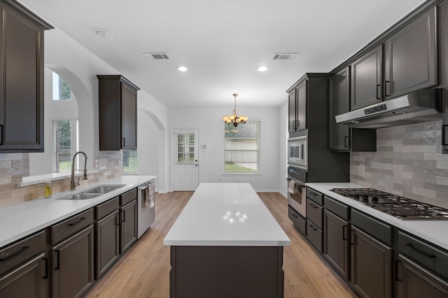 5918 Mahogany Way, Magnolia, TX 77354 - kitchen featuring appliances with stainless steel finishes, arched walkways, under cabinet range hood, a kitchen island, and light countertops