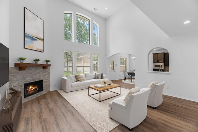 5918 Mahogany Way, Magnolia, TX 77354 - living area with arched walkways, high vaulted ceiling, a fireplace, wood finished floors, and recessed lighting