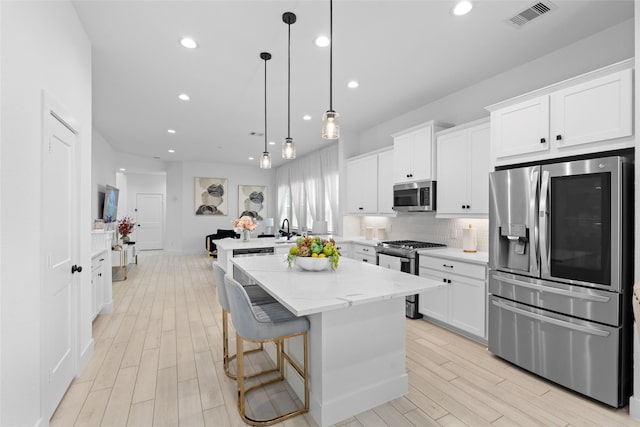 17735 Tree Of Heaven, Conroe, TX 77385 - kitchen with appliances with stainless steel finishes, white cabinets, light wood-style flooring, tasteful backsplash, and a kitchen island