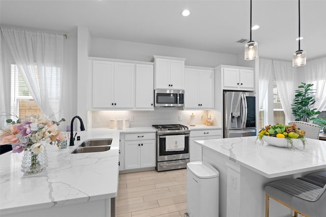 17735 Tree Of Heaven, Conroe, TX 77385 - kitchen with appliances with stainless steel finishes, tasteful backsplash, a kitchen island, white cabinetry, and light stone counters
