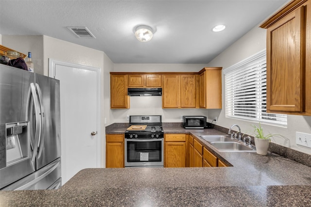 4714 Rumbling Canyon Ct, Katy, TX 77449 - kitchen with stainless steel appliances, under cabinet range hood, dark countertops, and brown cabinetry