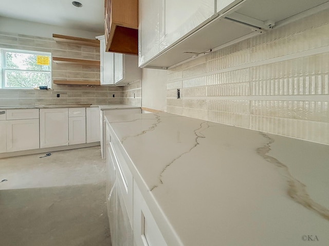 10651 Mayfield Rd, Houston, TX 77043 - kitchen with backsplash, light stone counters, white cabinets, concrete flooring, and open shelves