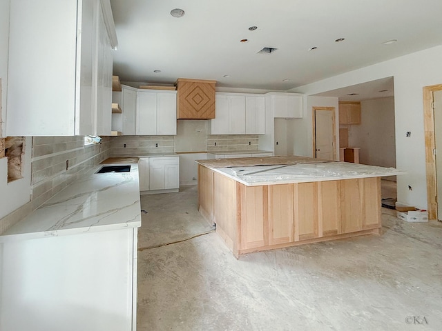10651 Mayfield Rd, Houston, TX 77043 - kitchen featuring backsplash, concrete flooring, white cabinetry, and a center island