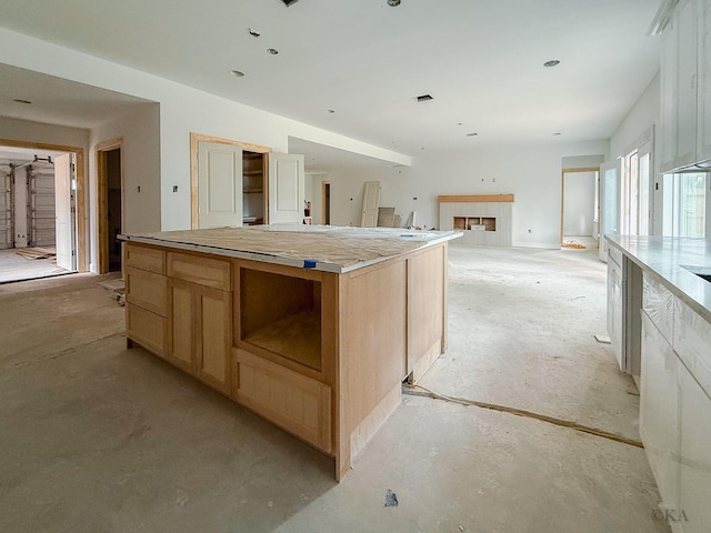 10651 Mayfield Rd, Houston, TX 77043 - kitchen with light brown cabinets, concrete floors, a tile fireplace, and a kitchen island