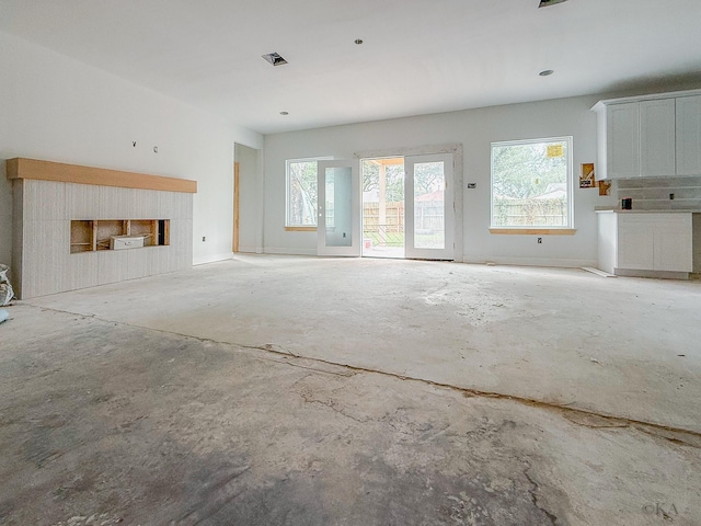 10651 Mayfield Rd, Houston, TX 77043 - unfurnished living room featuring healthy amount of natural light, a fireplace, and unfinished concrete flooring