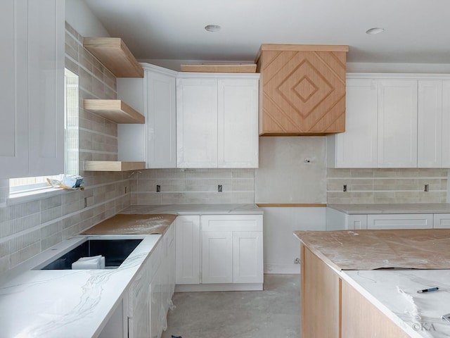 10651 Mayfield Rd, Houston, TX 77043 - kitchen featuring open shelves, light stone countertops, decorative backsplash, and white cabinetry