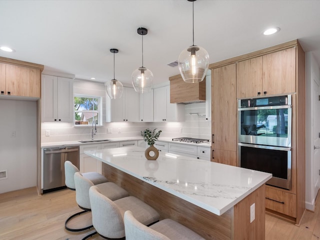 10651 Mayfield Rd, Houston, TX 77043 - kitchen featuring stainless steel appliances, decorative backsplash, light wood-style floors, a kitchen breakfast bar, and recessed lighting