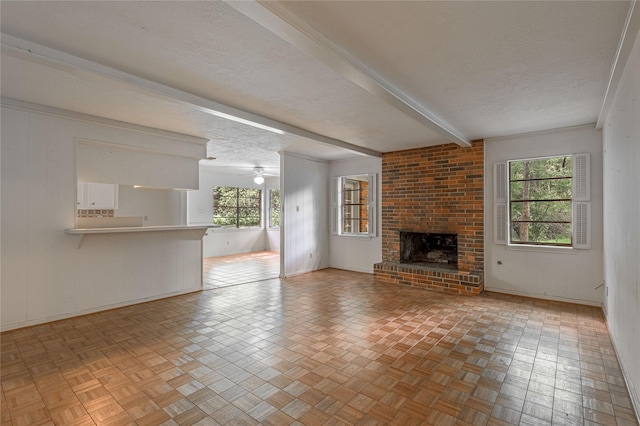 3799 Summer Ln, Huntsville, TX 77340 - unfurnished living room with a textured ceiling, a brick fireplace, ceiling fan, and beamed ceiling