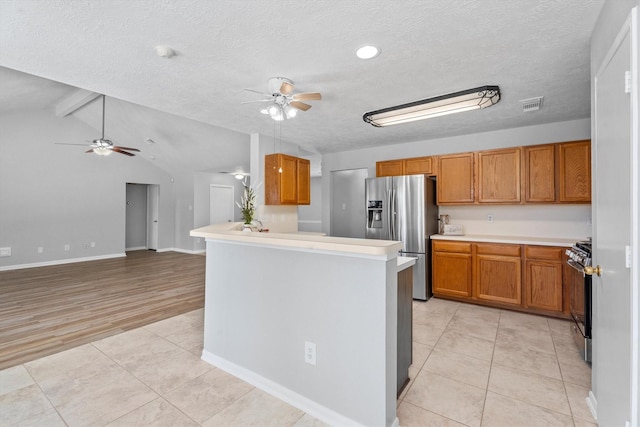14306 Cypress Meadow Dr, Cypress, TX 77429 - kitchen with stainless steel fridge, ceiling fan, range, brown cabinetry, and a textured ceiling