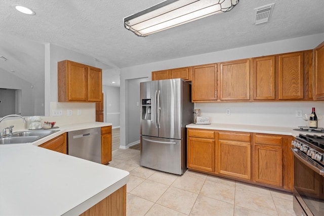 14306 Cypress Meadow Dr, Cypress, TX 77429 - kitchen featuring stainless steel appliances, light countertops, brown cabinets, a textured ceiling, and light tile patterned floors