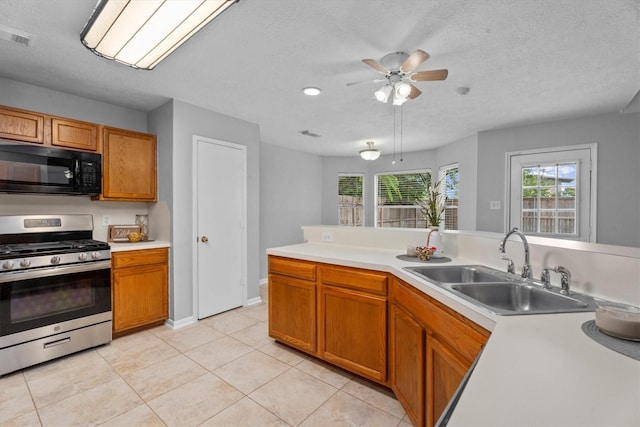 14306 Cypress Meadow Dr, Cypress, TX 77429 - kitchen with stainless steel gas range, black microwave, ceiling fan, light countertops, and a textured ceiling