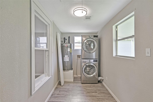 2131 6th Ave N, Texas City, TX 77590 - laundry room featuring electric water heater, stacked washer / drying machine, wood finished floors, a textured wall, and a textured ceiling