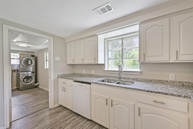 2131 6th Ave N, Texas City, TX 77590 - kitchen with white dishwasher, stacked washer / drying machine, light wood-style flooring, light stone countertops, and white cabinetry