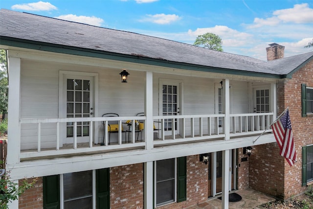 8114 Coolshire Ln, Houston, TX 77070 - rear view of house featuring a balcony, brick siding, a shingled roof, and a chimney