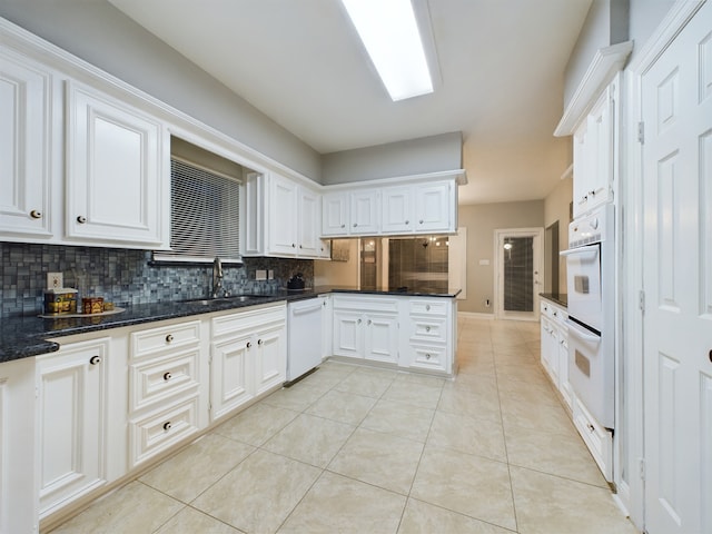 11614 Taos Ln, Houston, TX 77070 - kitchen with white appliances, backsplash, light tile patterned floors, white cabinets, and dark stone counters
