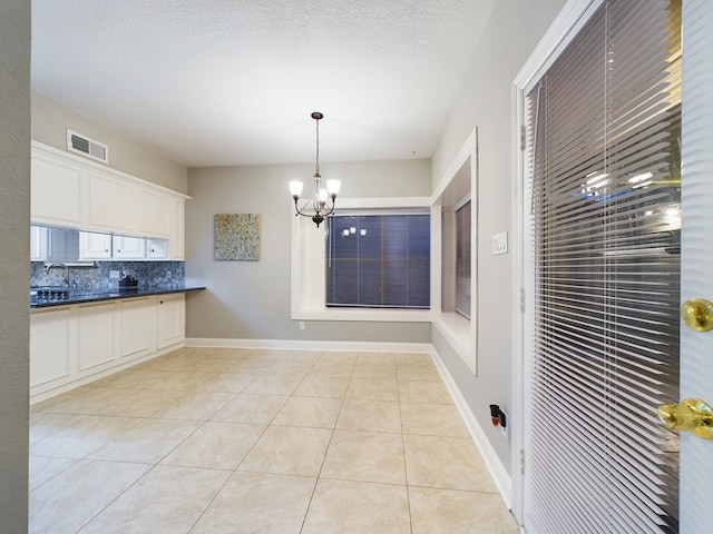 11614 Taos Ln, Houston, TX 77070 - kitchen featuring dark countertops, tasteful backsplash, light tile patterned floors, a chandelier, and white cabinetry