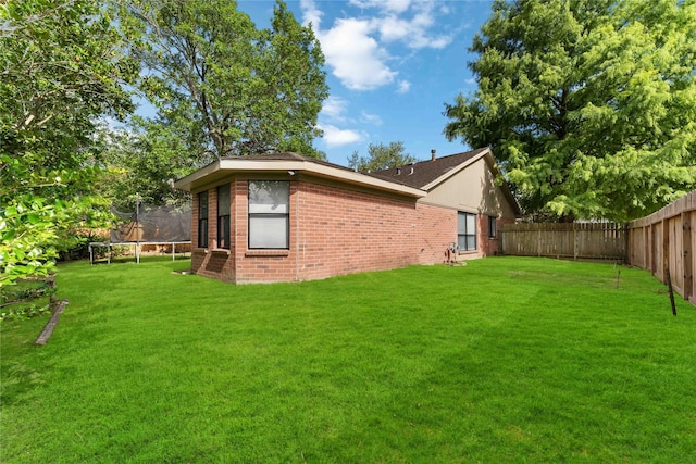 1710 Blue Heather Ln, Fresno, TX 77545 - view of side of home with a trampoline, a fenced backyard, and brick siding