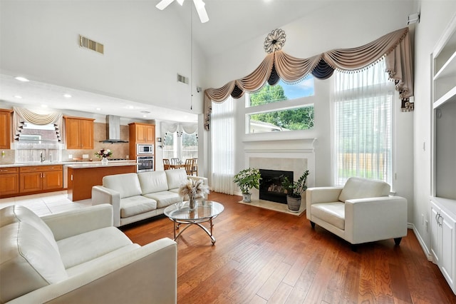 21306 Willowford Park Dr, Katy, TX 77450 - living room with plenty of natural light, light wood-style floors, a fireplace with flush hearth, ceiling fan, and a towering ceiling