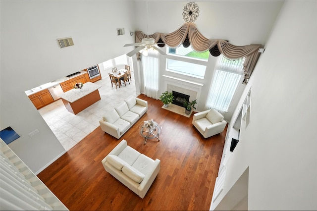 21306 Willowford Park Dr, Katy, TX 77450 - living area featuring a towering ceiling, a ceiling fan, light wood-style flooring, and a premium fireplace