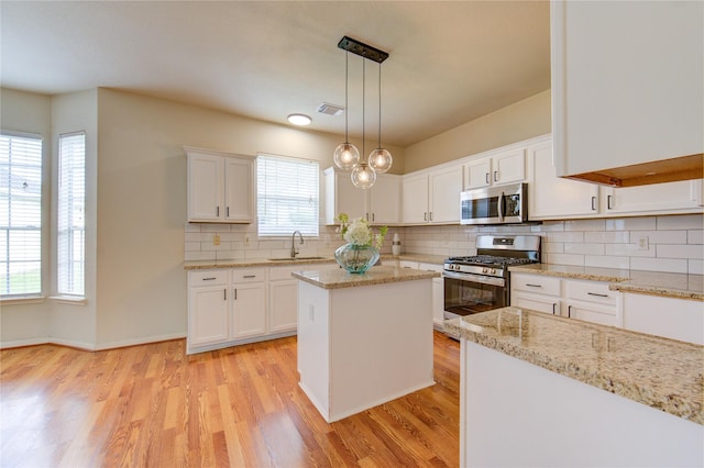 21306 Branford Hills Ln, Katy, TX 77450 - kitchen with appliances with stainless steel finishes, light wood-style floors, white cabinets, decorative backsplash, and decorative light fixtures