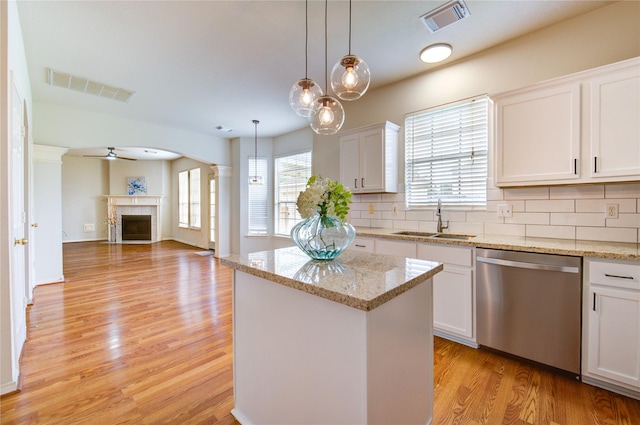 21306 Branford Hills Ln, Katy, TX 77450 - kitchen featuring stainless steel dishwasher, light wood finished floors, a ceiling fan, a kitchen island, and a fireplace