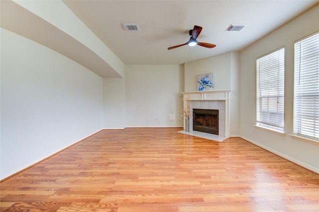 21306 Branford Hills Ln, Katy, TX 77450 - unfurnished living room featuring a tiled fireplace, light wood-type flooring, and a ceiling fan