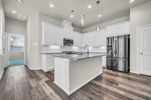 16114 Northern Cardinal Ln, Cypress, TX 77433 - kitchen featuring appliances with stainless steel finishes, dark wood-type flooring, decorative backsplash, dark stone countertops, and a center island with sink